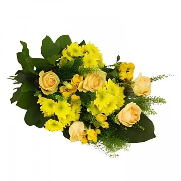 En liggande begravningsbukett med gula snittblommor och grönt.
