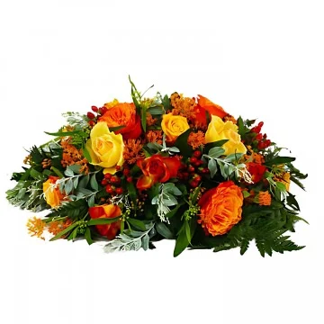 En låg begravningsdekoration med röda och orange snittblommor och grönt.