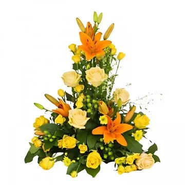 En hög begravningsdekoration med orange och aprikosa snittblommor och grönt.