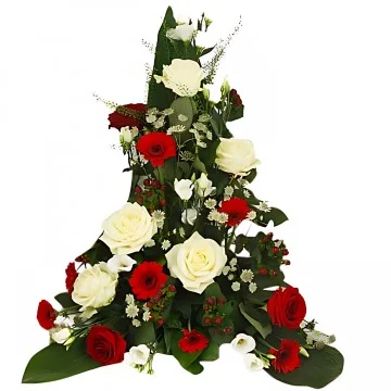 En hög begravningsdekoration med röda och vita snittblommor och grönt.