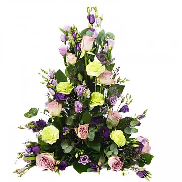 En hög begravningsdekoration med rosa, lila och vita snittblommor och grönt.